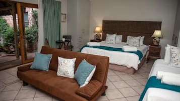 A hotel room with two beds, a sofa, and a small table.