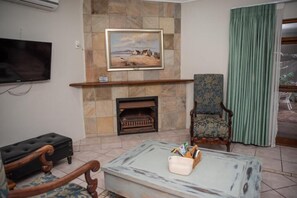 Sala de estar com lareira, televisão e cortina verde.