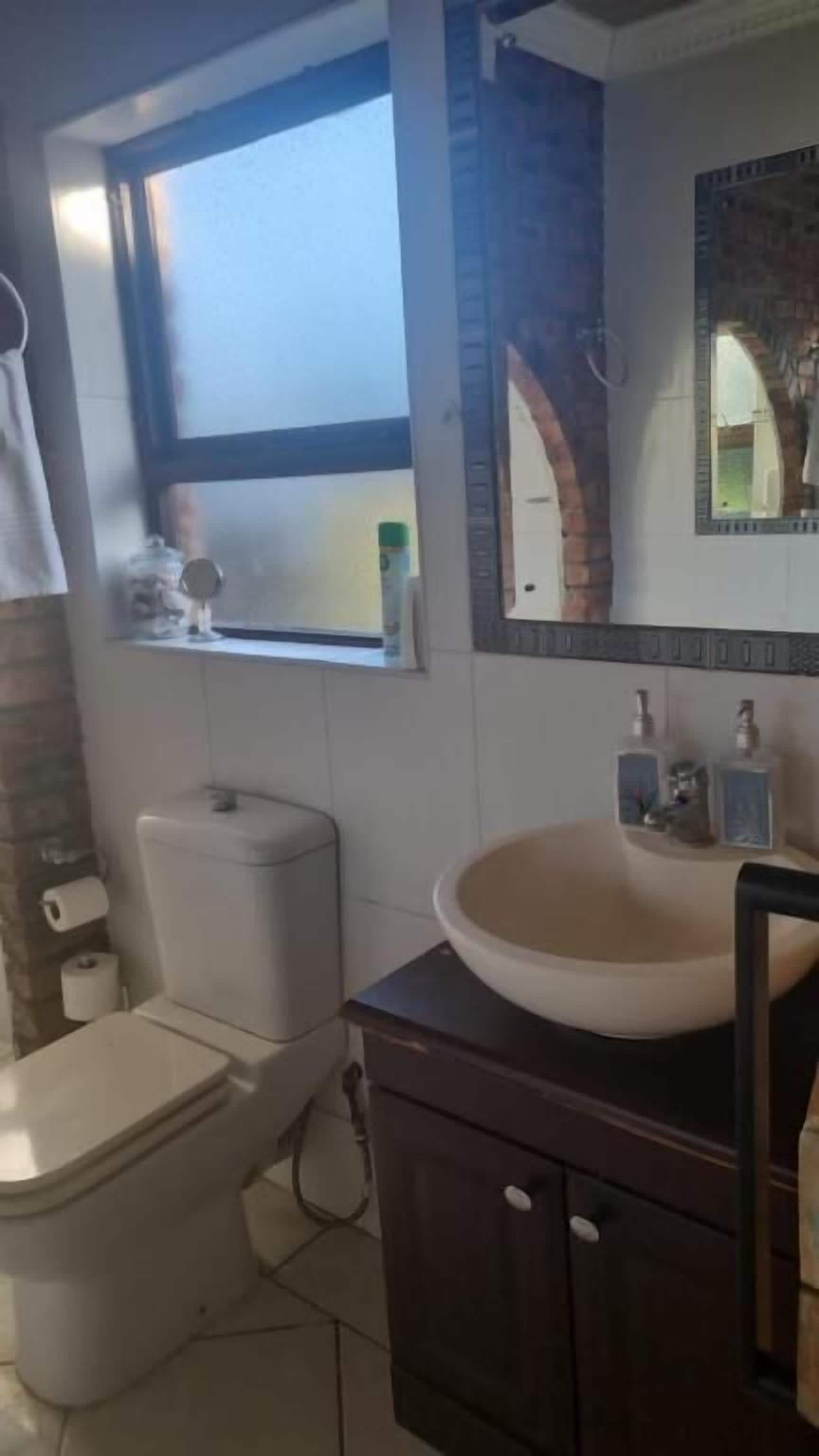 A bathroom with a toilet, sink, and window.