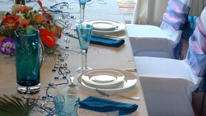 A table set for a meal with blue napkins, clear glassware, and a floral centerpiece. - Bluewater Reservations (Gqeberha (Port Elizabeth))