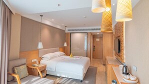 Una habitación de hotel moderna con una cama grande, mesitas de noche, un televisor y una chimenea.