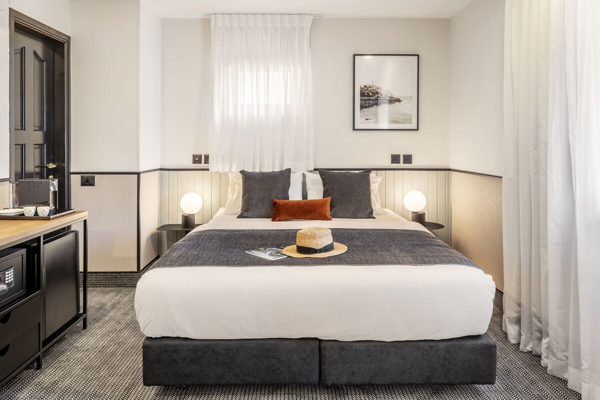 Een hotelkamer met een bed, nachtkastjes, een bureau en een koffieapparaat.