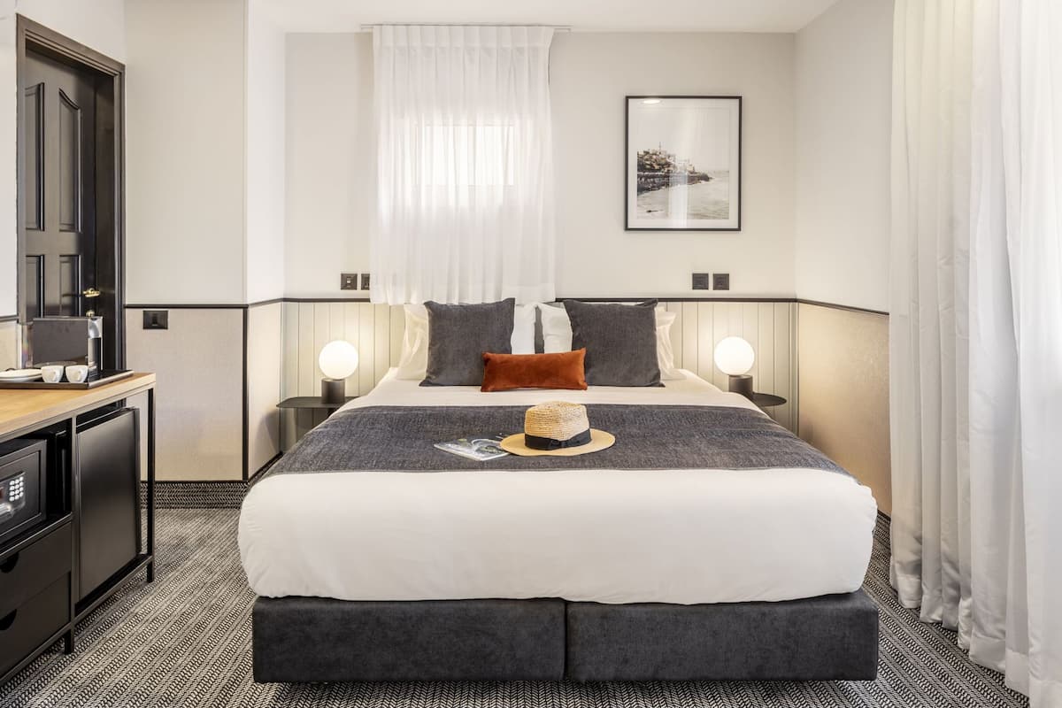 A hotel room with a bed, bedside tables, a desk, and a coffee machine.