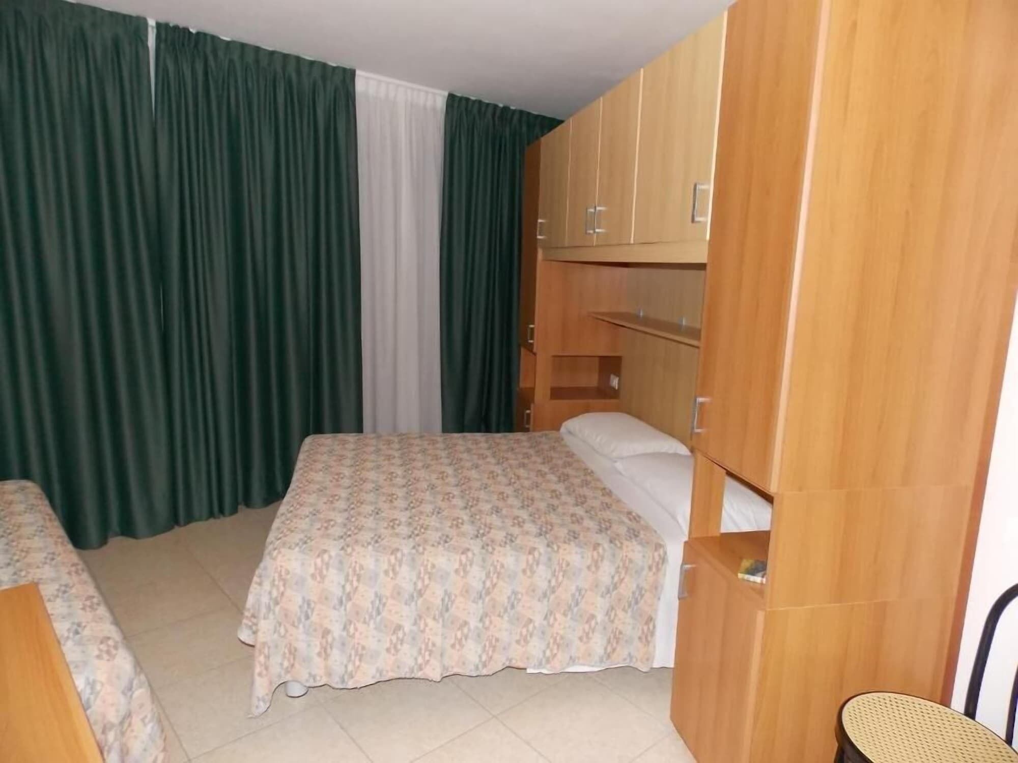 A bedroom with a bed, a wooden wardrobe, and a chair.