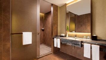 Une salle de bain moderne avec un grand miroir, un comptoir en marbre et un porte-serviettes.