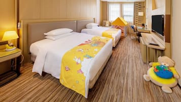 A hotel room with two beds, a desk, a television, and a teddy bear.