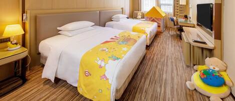A hotel room with two beds, a desk, a television, and a teddy bear.