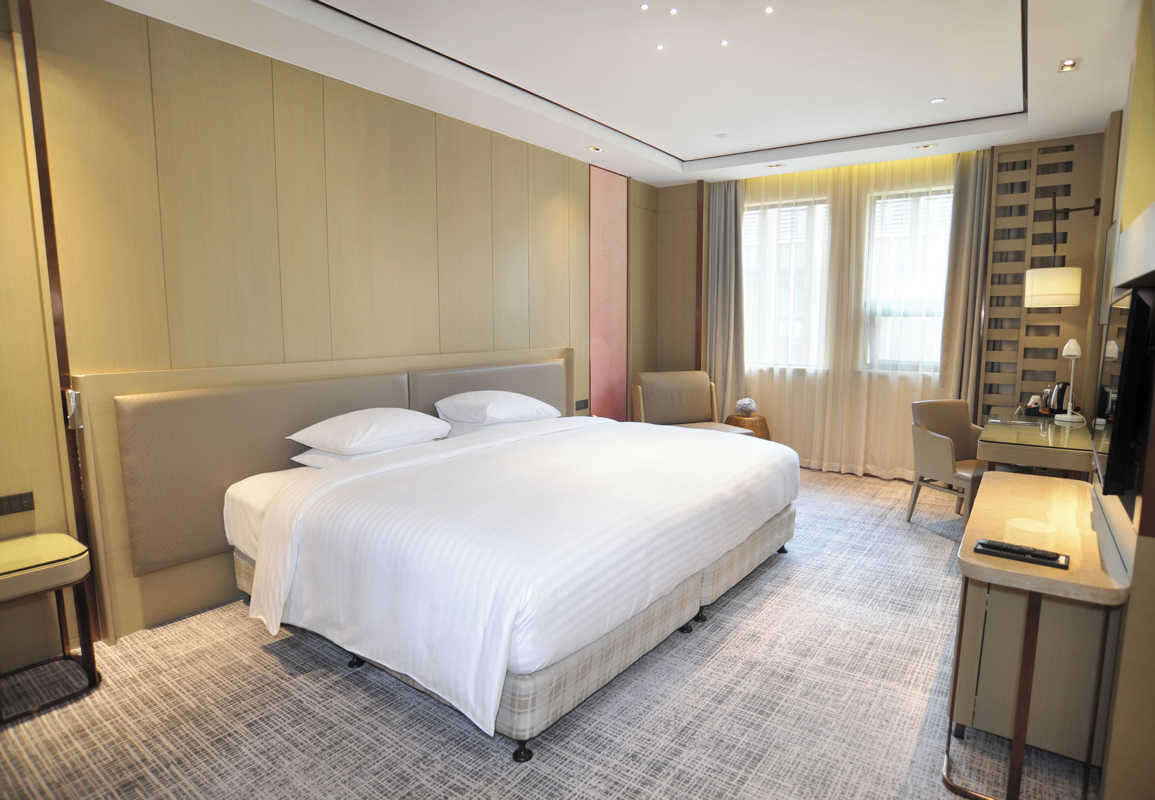 Ein Hotelzimmer mit einem großen Bett, einem Schreibtisch mit Lampe und einem Sessel.