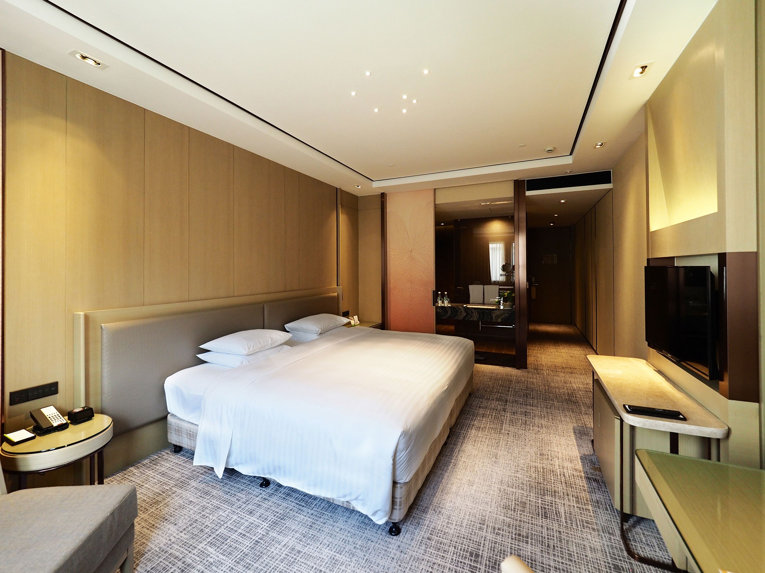 A hotel room with a large bed, bedside table, and a TV.