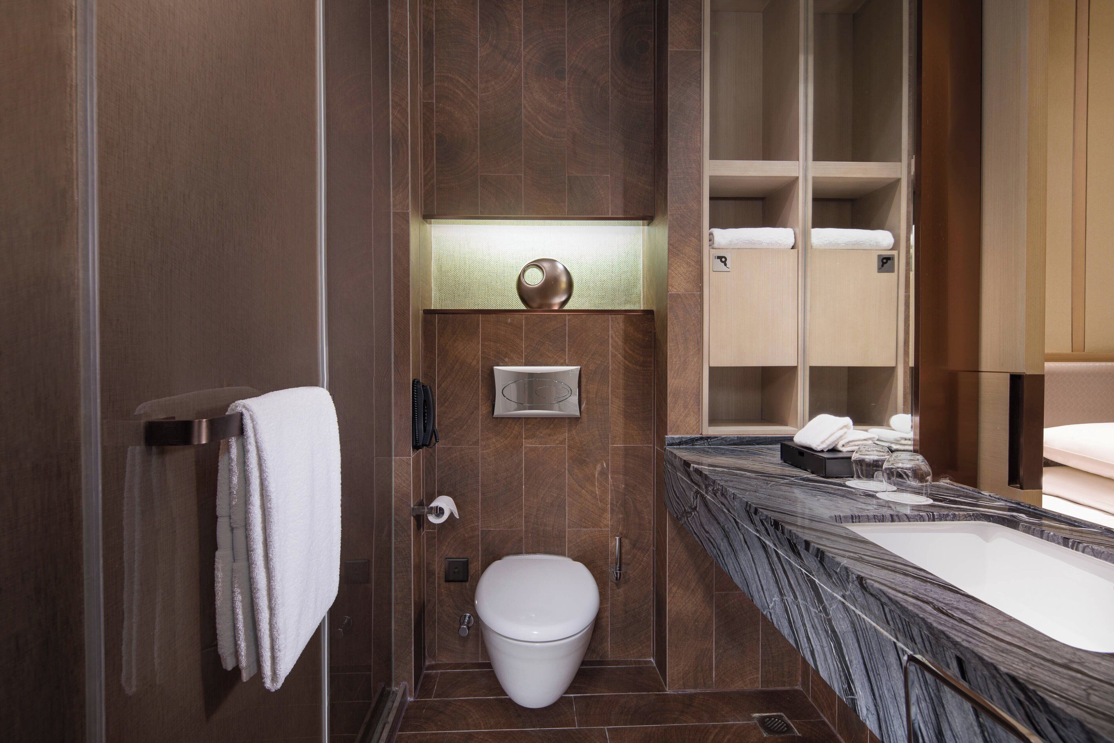 Un baño moderno con inodoro, lavamanos y espejo.