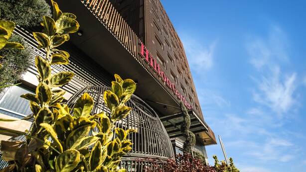 Un hotel con un diseño arquitectónico moderno, que destaca por su fachada curva y un letrero que indica que es un hotel.