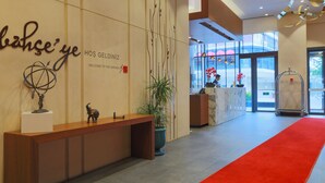 Un área de recepción con un mostrador de madera, una alfombra roja y una pared con un letrero que dice "bahse'ye" y "HOŞ GELDİNIZ".