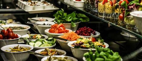 A buffet with various dishes including salads, vegetables, and garnishes.