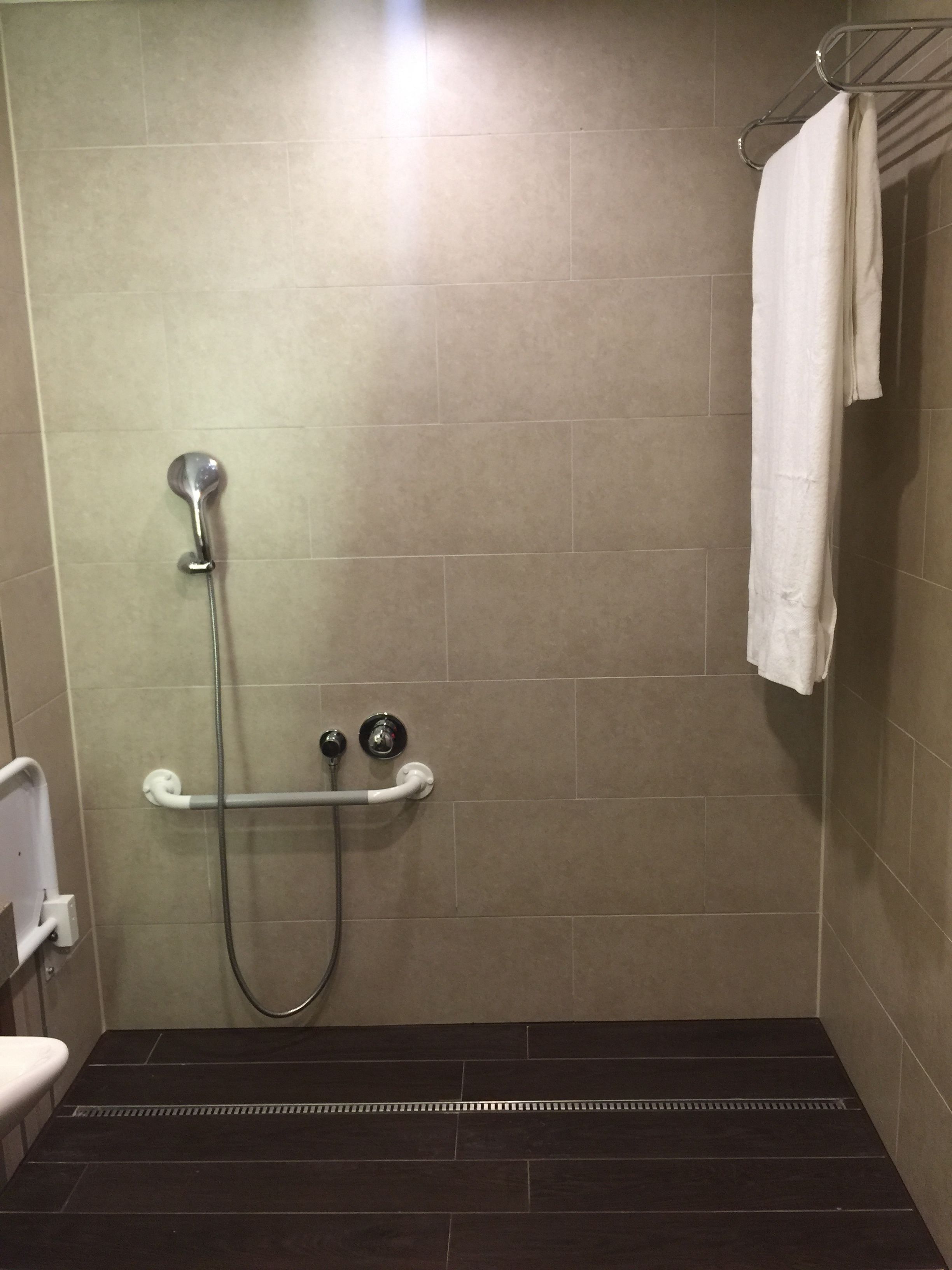 Un espace douche équipé d’un pommeau de douche à main, d’un robinet mural et d’un porte-serviettes.