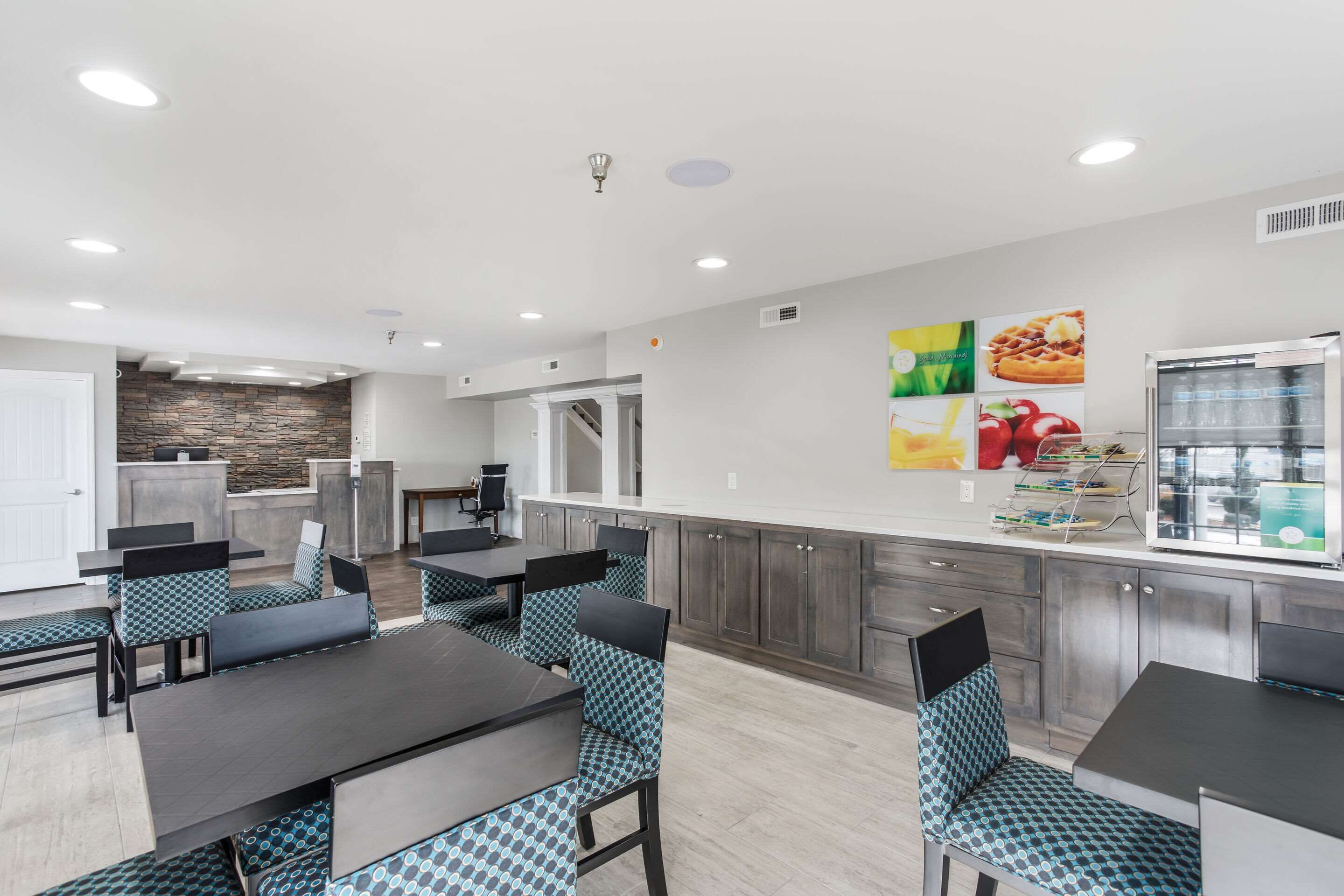 A modern kitchen with a stone backsplash, a refrigerator, and a dining area with patterned chairs and tables.