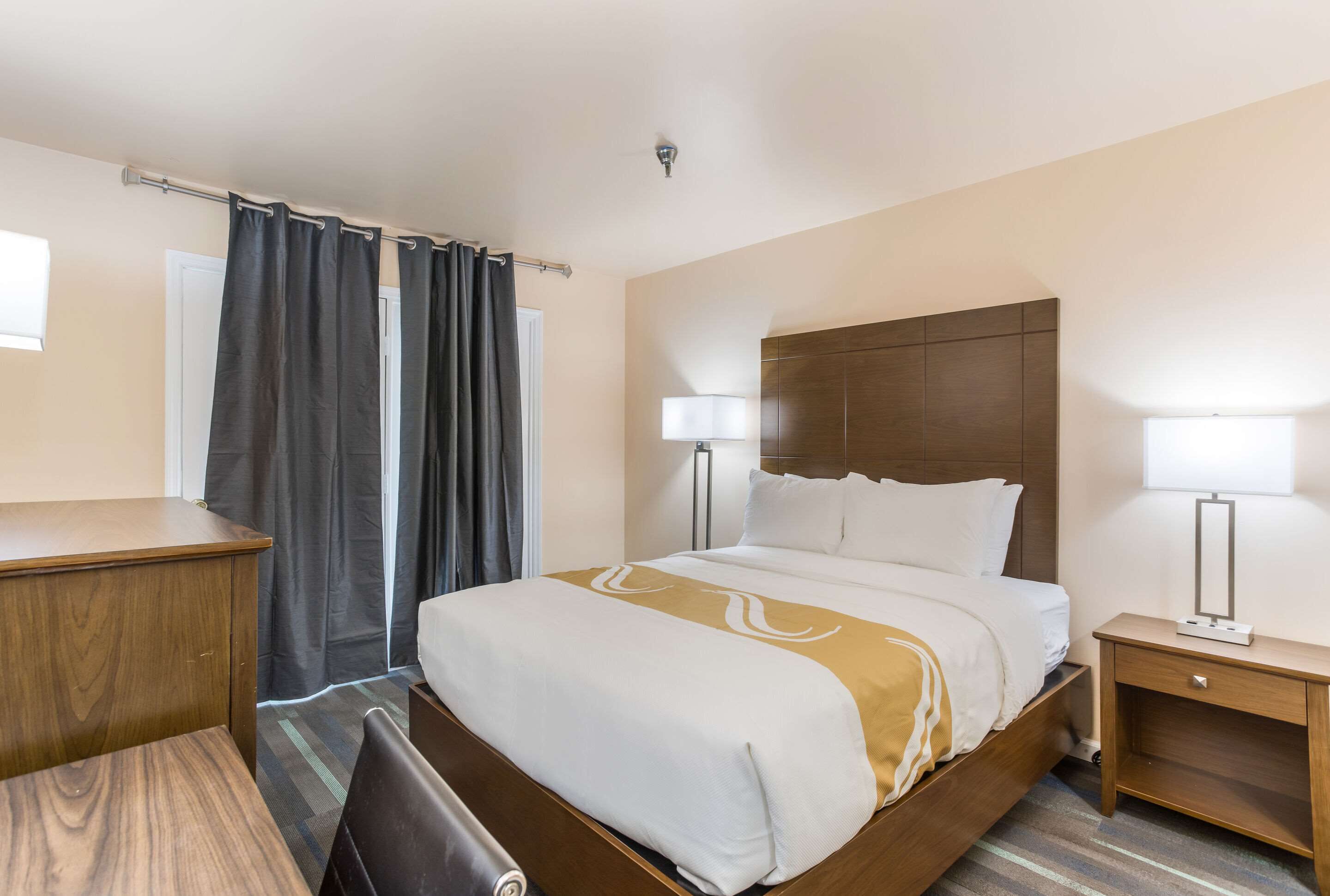 Habitació d'hotel amb llit, taules de nit, escriptori i una cadira.