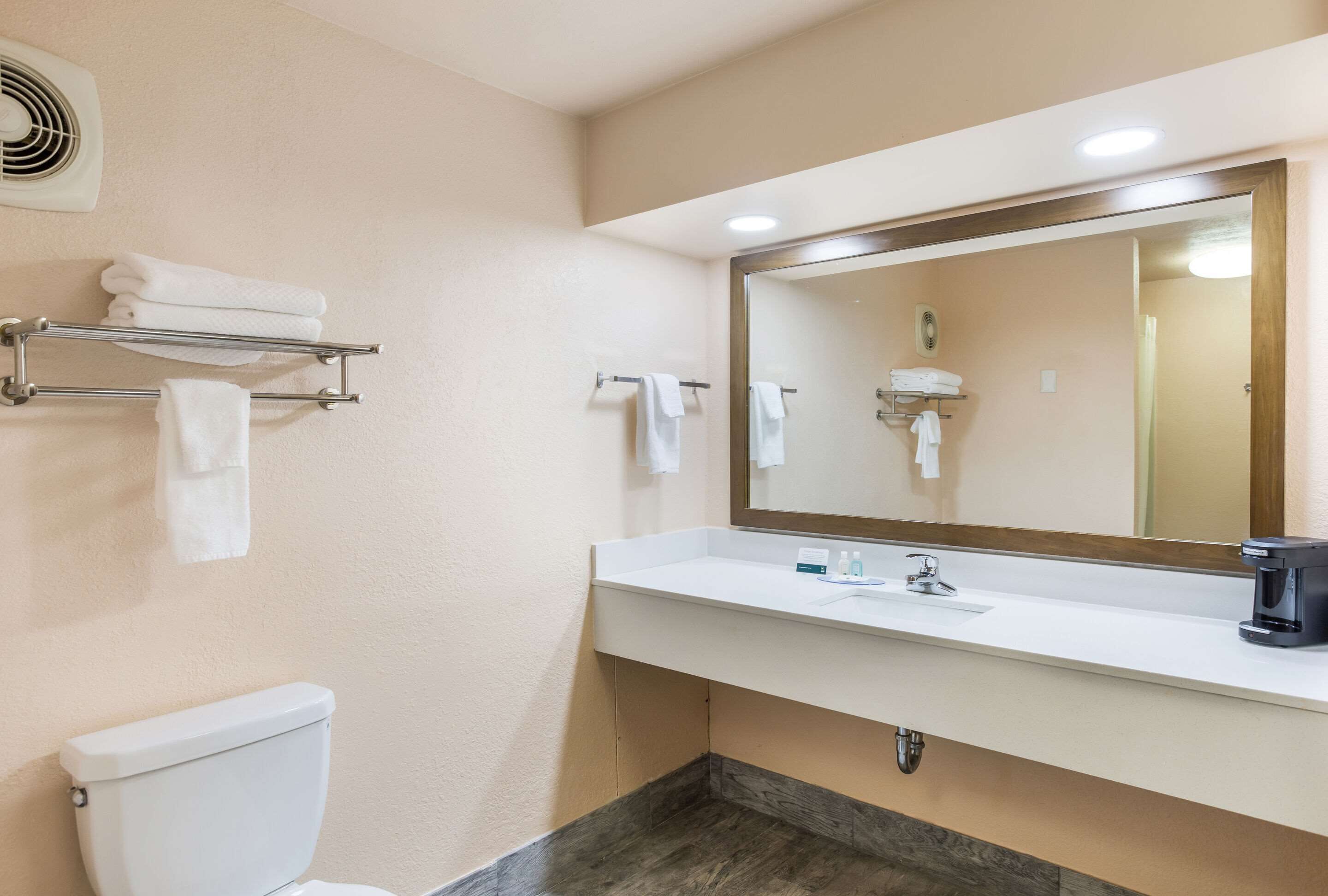 A bathroom with a white toilet, a sink with a mirror, and a towel rack.