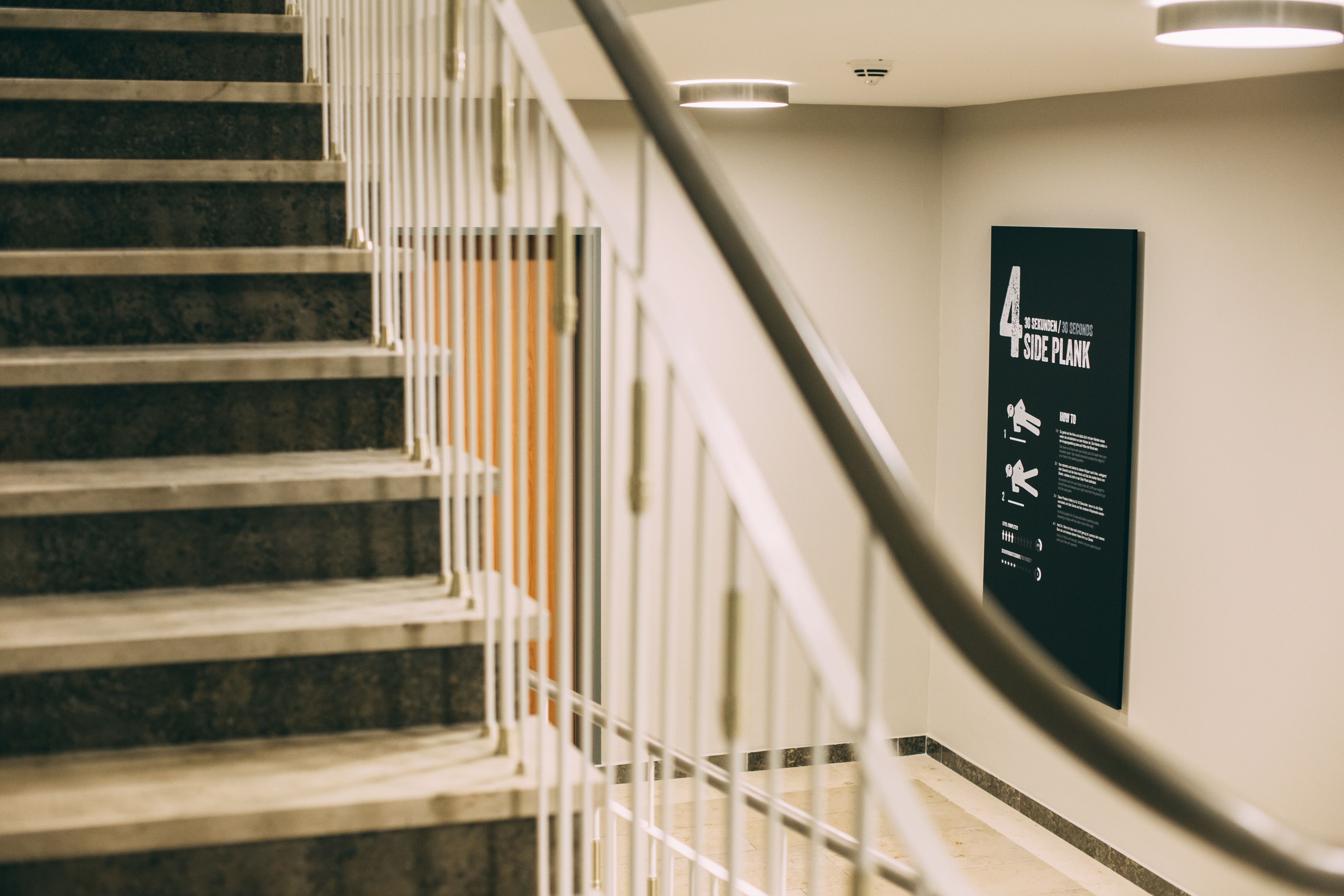 A staircase with a handrail and a poster on the wall.