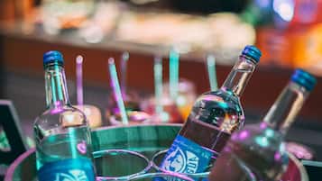 A wooden barrel filled with bottles of alcohol and glasses, likely in a bar setting.