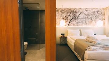 Una habitación de hotel con cama, mesita de noche y un mural de un árbol en la pared.