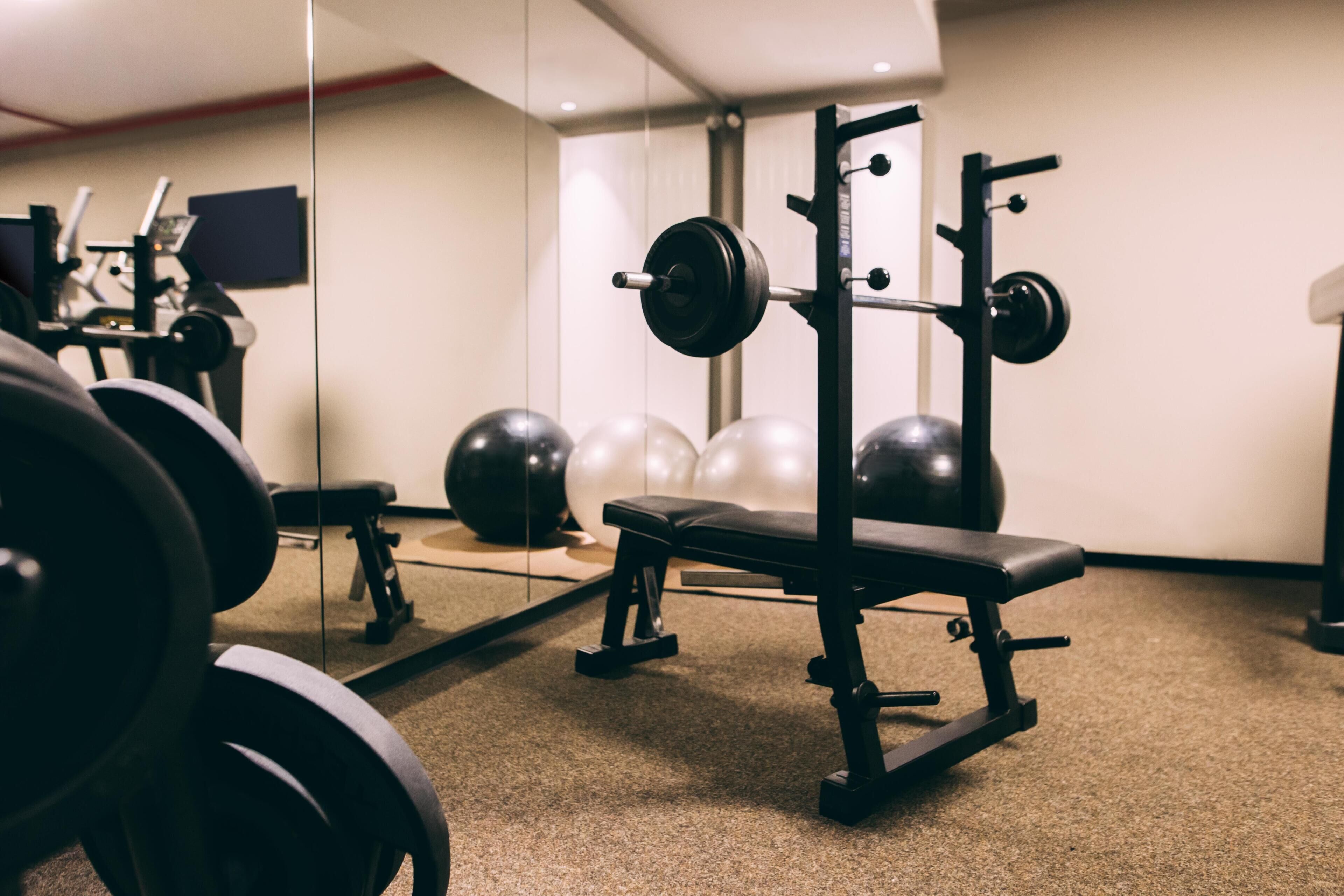 A gym with weightlifting equipment, a bench, and exercise balls.