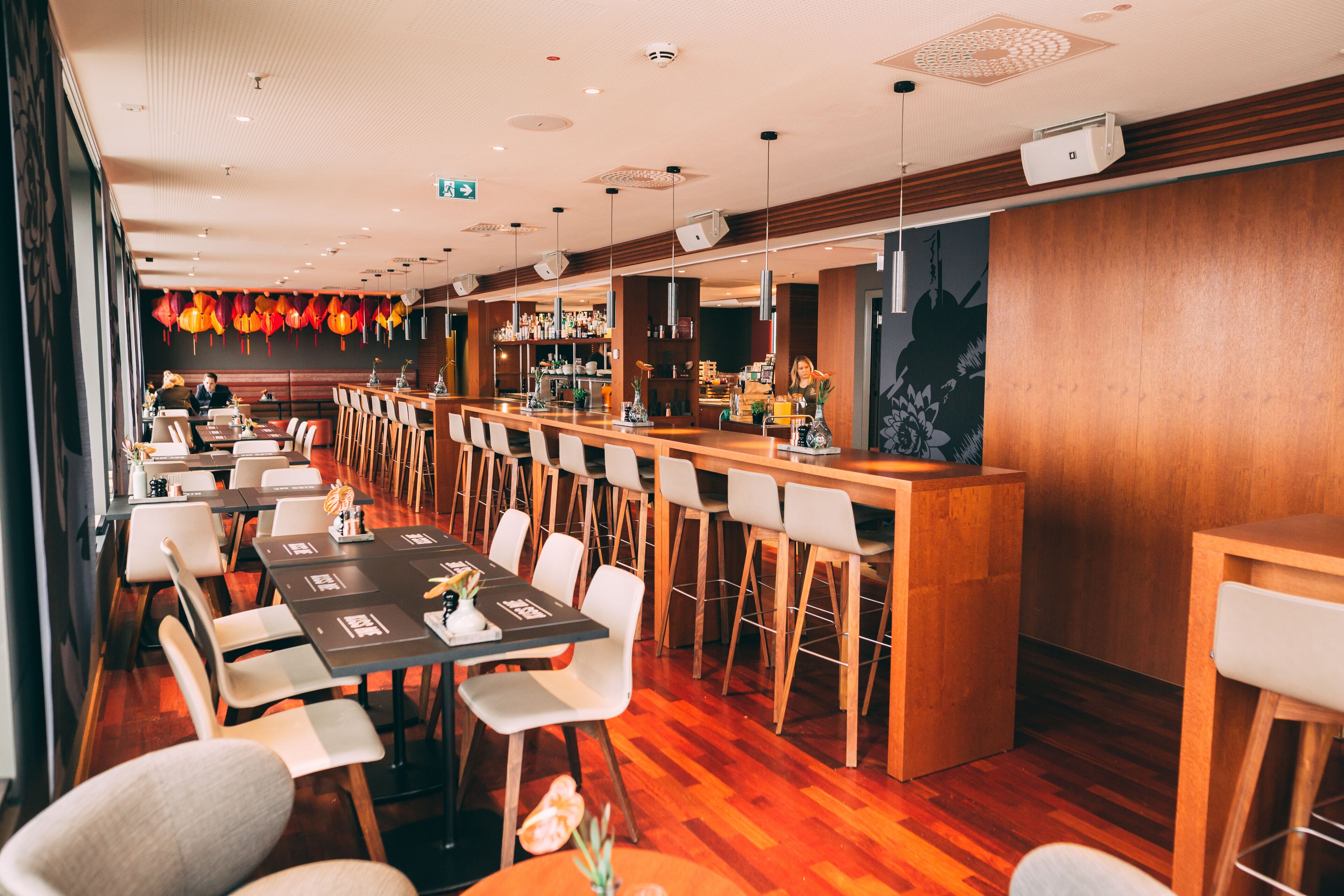 A restaurant with long communal tables, individual booths, and a bar area.