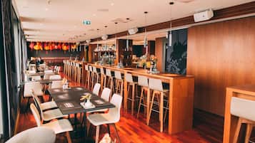 A restaurant with long communal tables, individual booths, and a bar area.