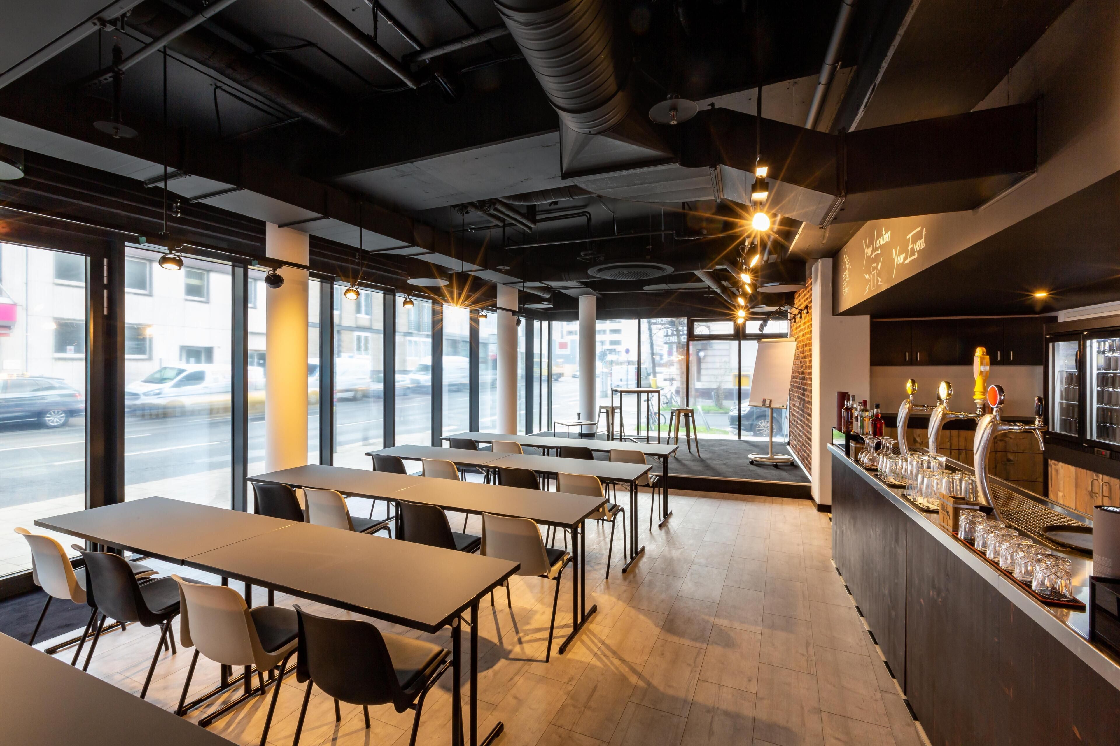 Un intérieur de restaurant moderne, avec des tables, des chaises, un bar et de grandes fenêtres.