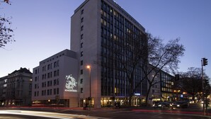 Un hotel de varios pisos con un letrero llamativo, amplias ventanas y un diseño arquitectónico moderno.