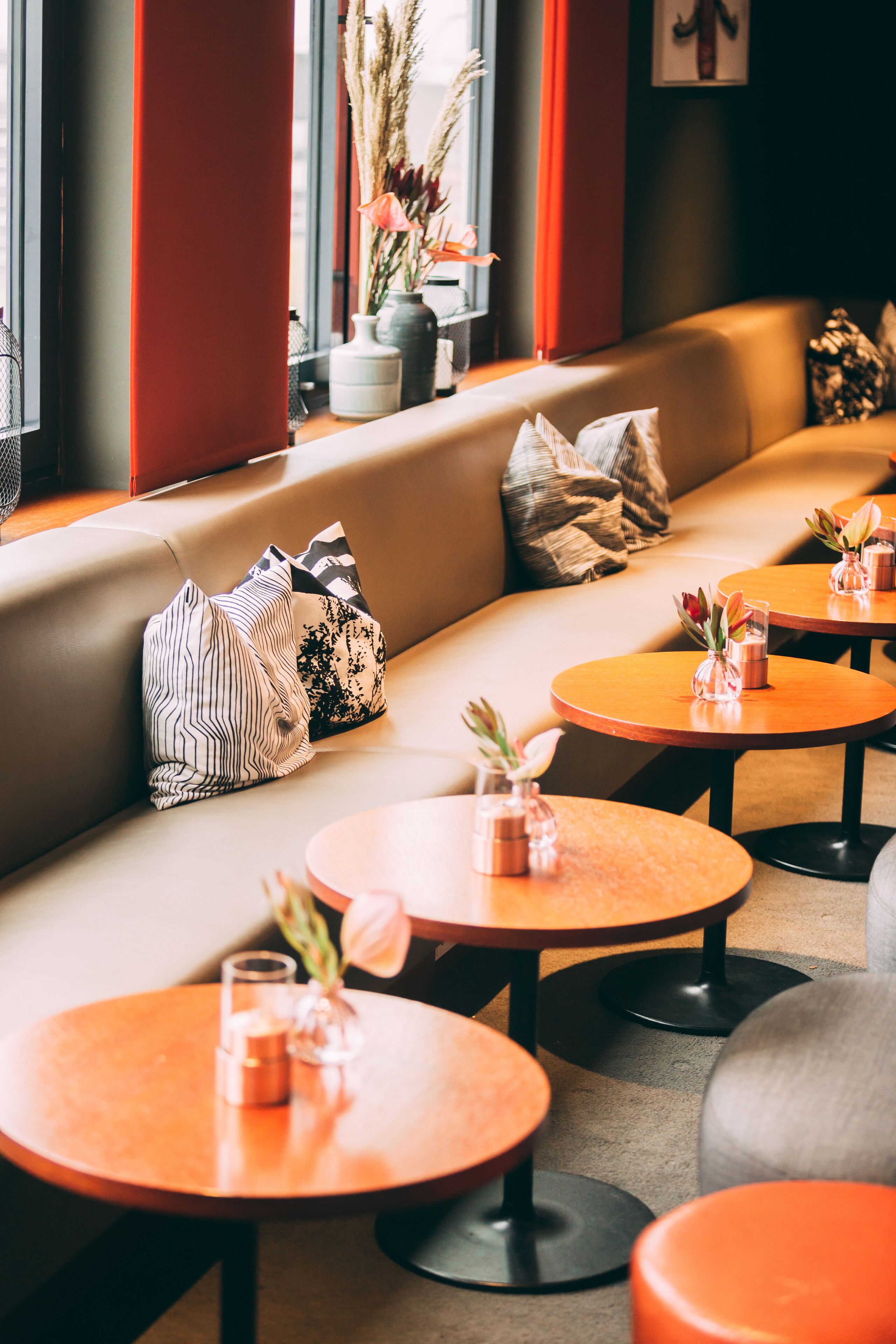A modern interior with a sofa and round tables, some with vases.