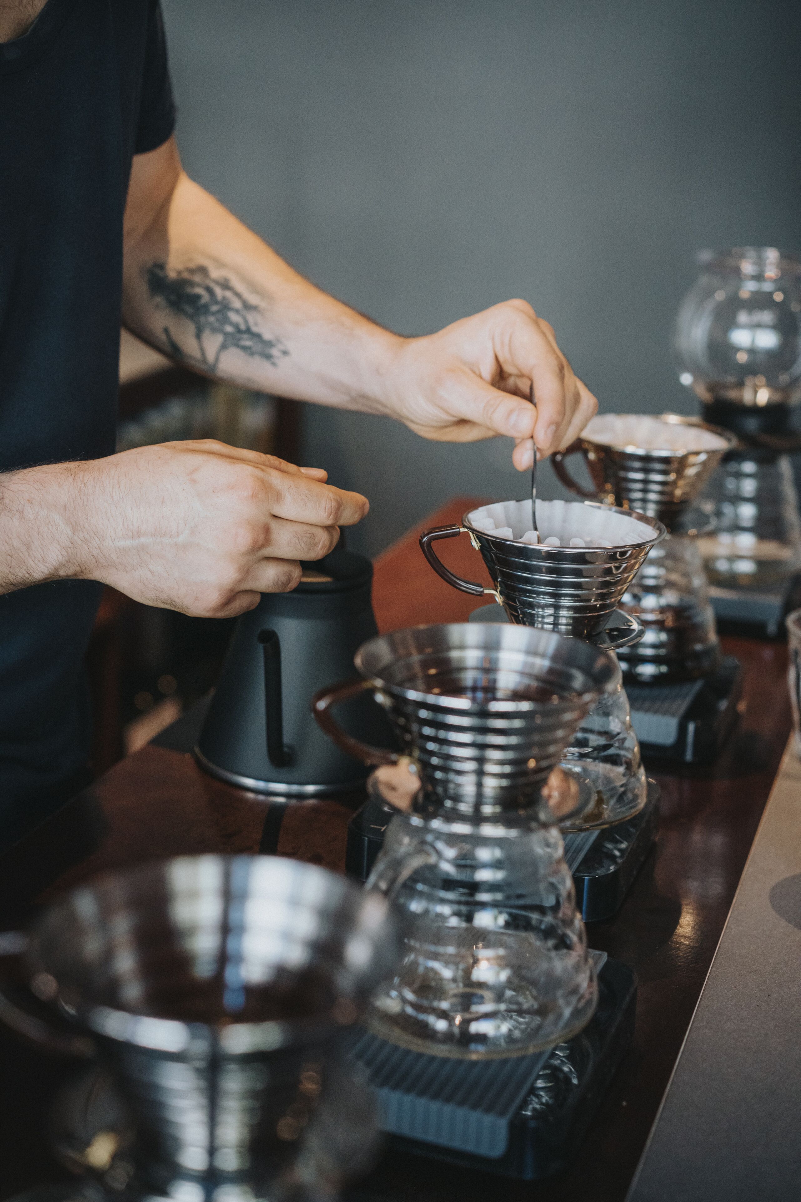 Una persona preparando café con una cafetera y varias tazas de café.