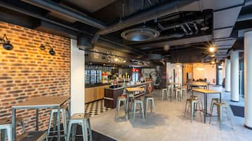 A modern bar area with exposed brick walls, metal stools, and a central bar counter.