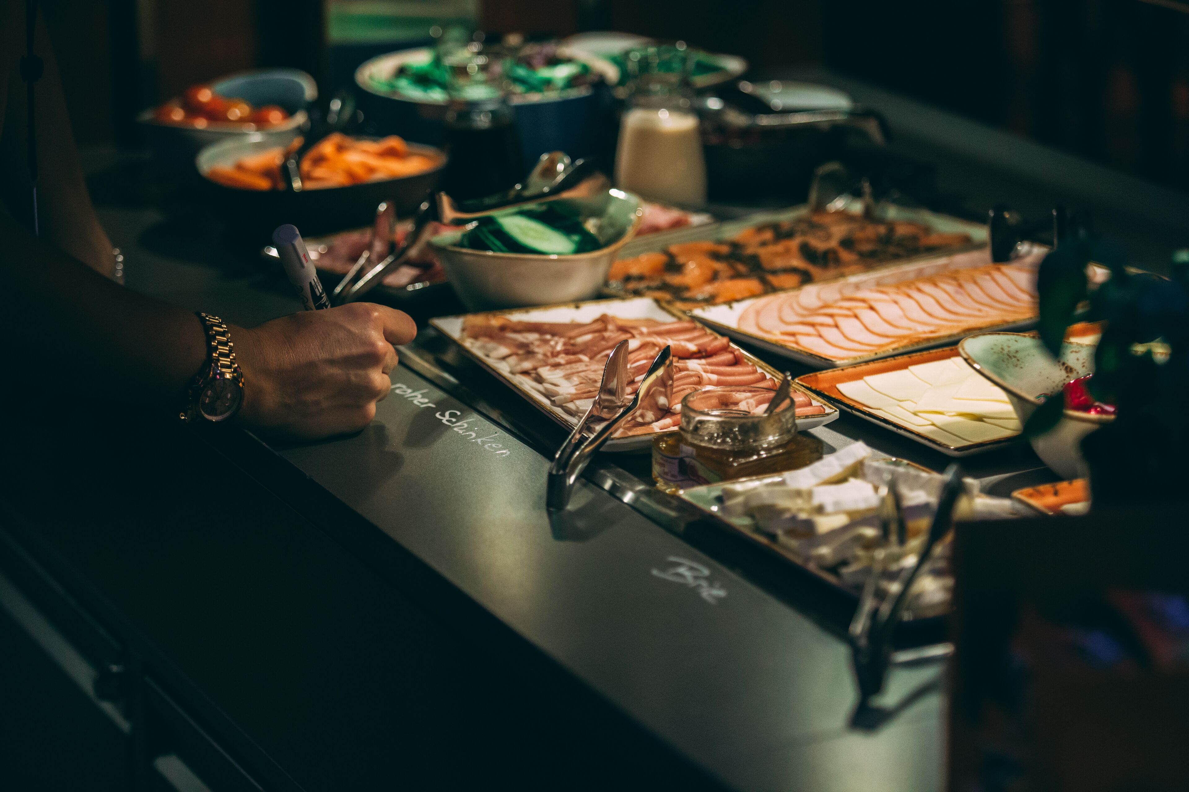 A buffet table with various food items and utensils.