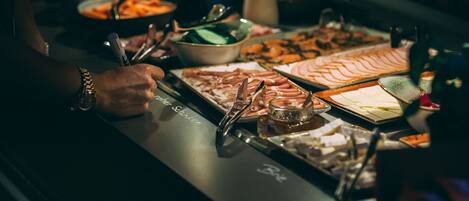 A buffet table with various food items and utensils.