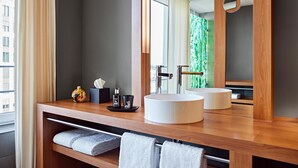 Un baño moderno con tocador de madera, dos lavamanos, un espejo grande y un perchero para toallas.