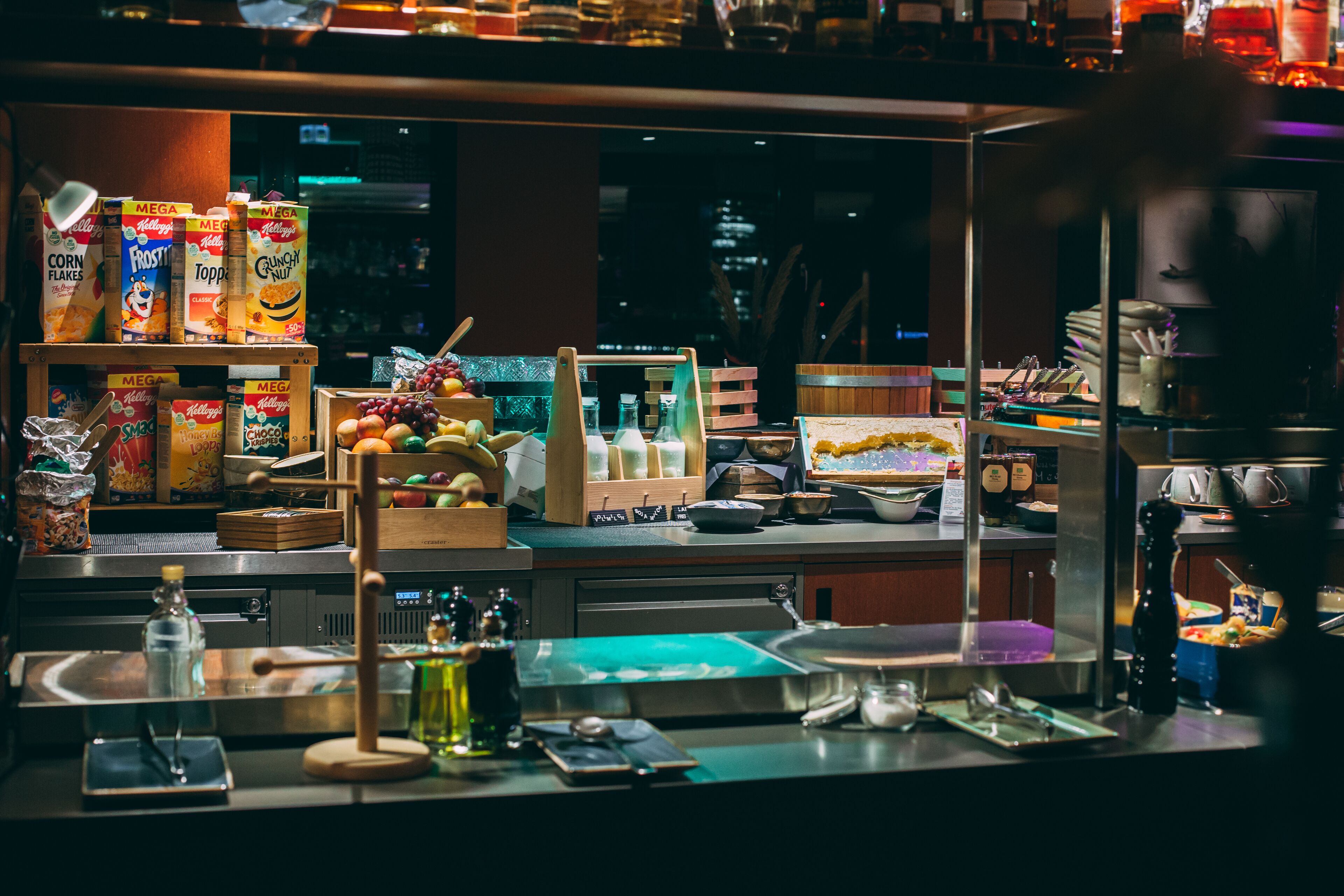 A breakfast bar with cereal boxes, fruits, and condiments.