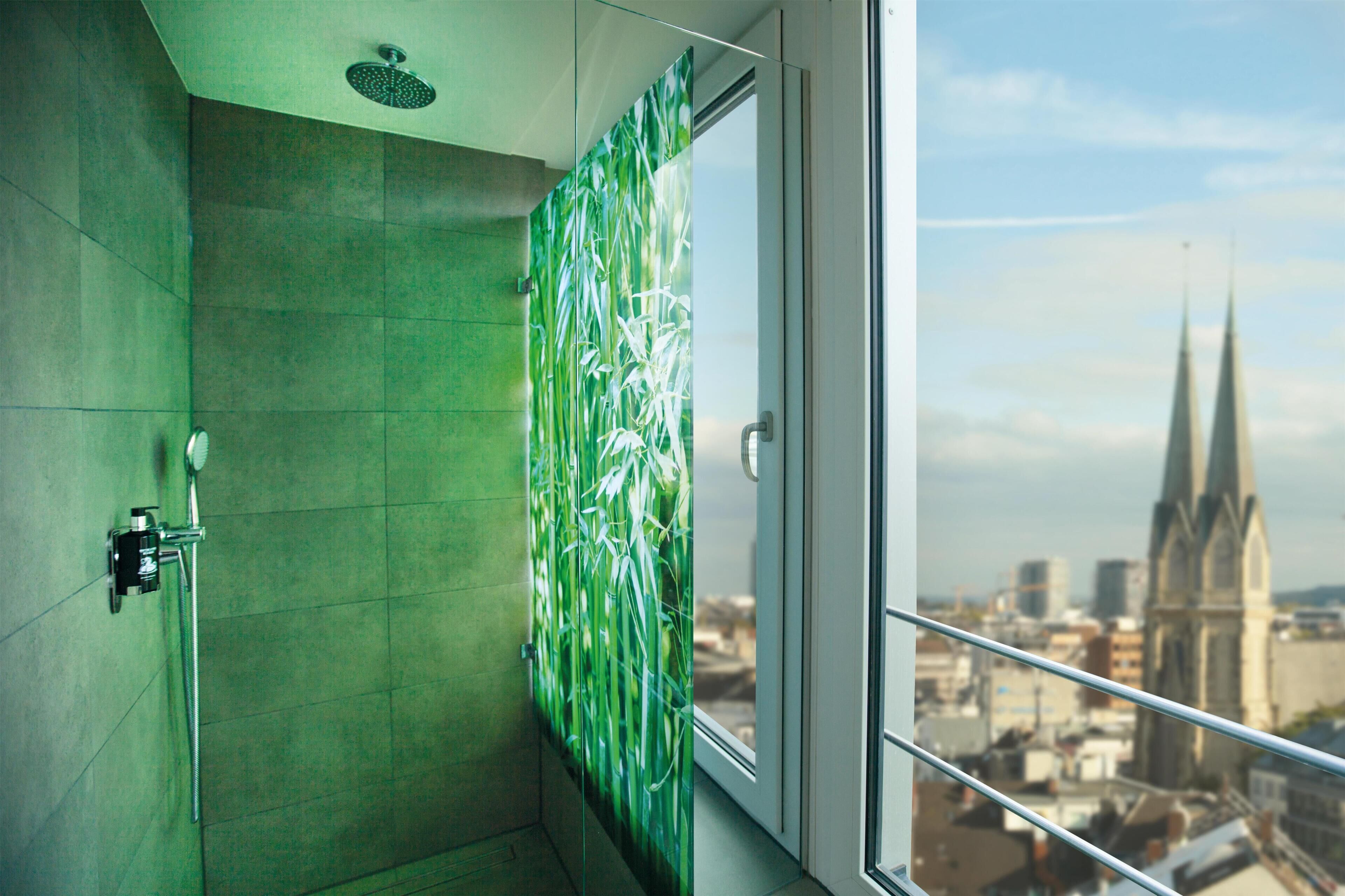 Un bagno con porta in vetro, doccia e vista sulla città.