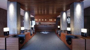 Un moderno vestíbulo de hotel con un mostrador de recepción central, varios orinales y un logotipo en la pared.