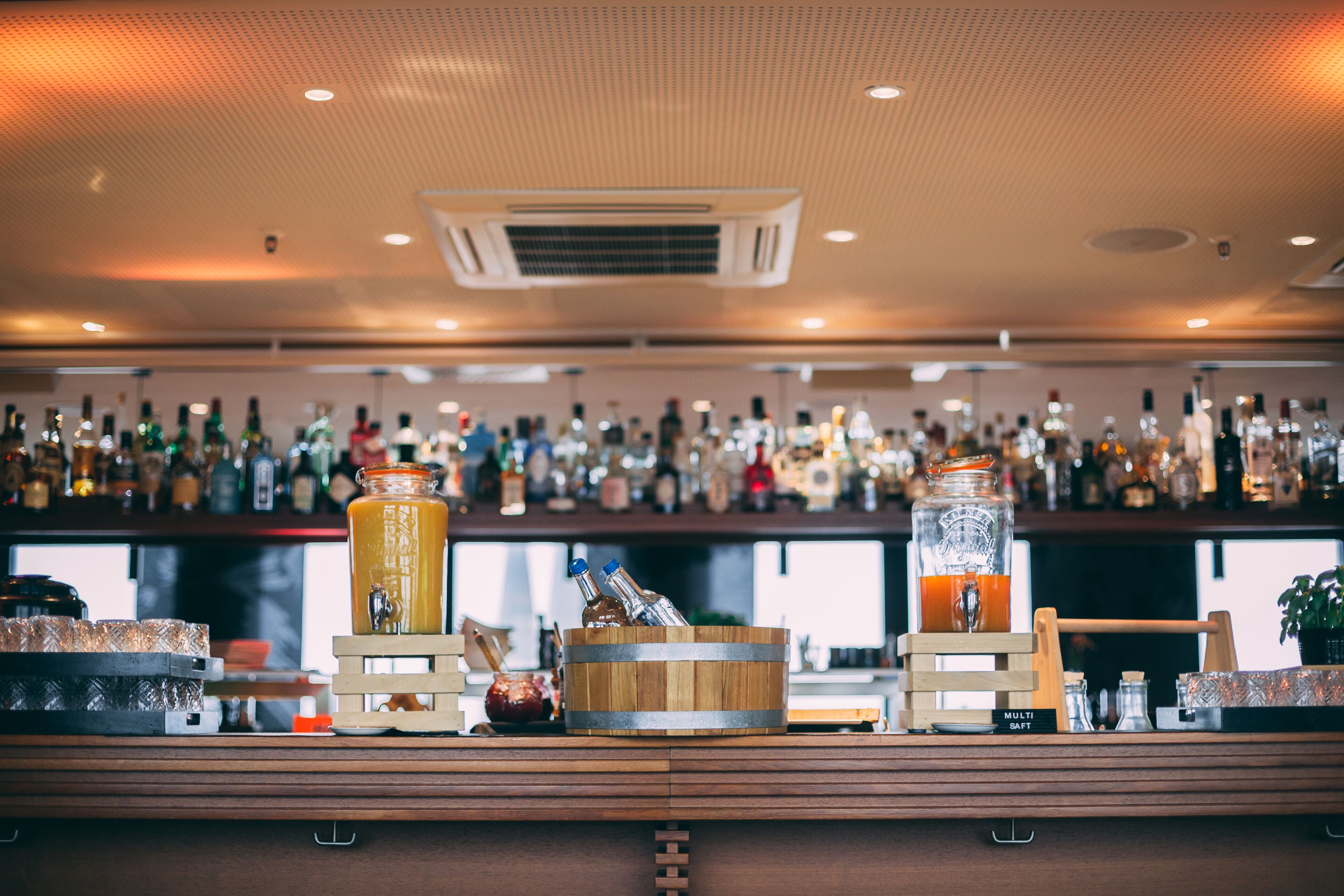 Zona de bar con una variedad de botellas y una barrica de madera.