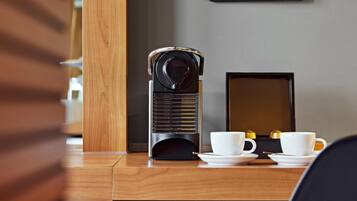 A wooden desk with a coffee maker, two white cups, and a framed certificate on the wall.