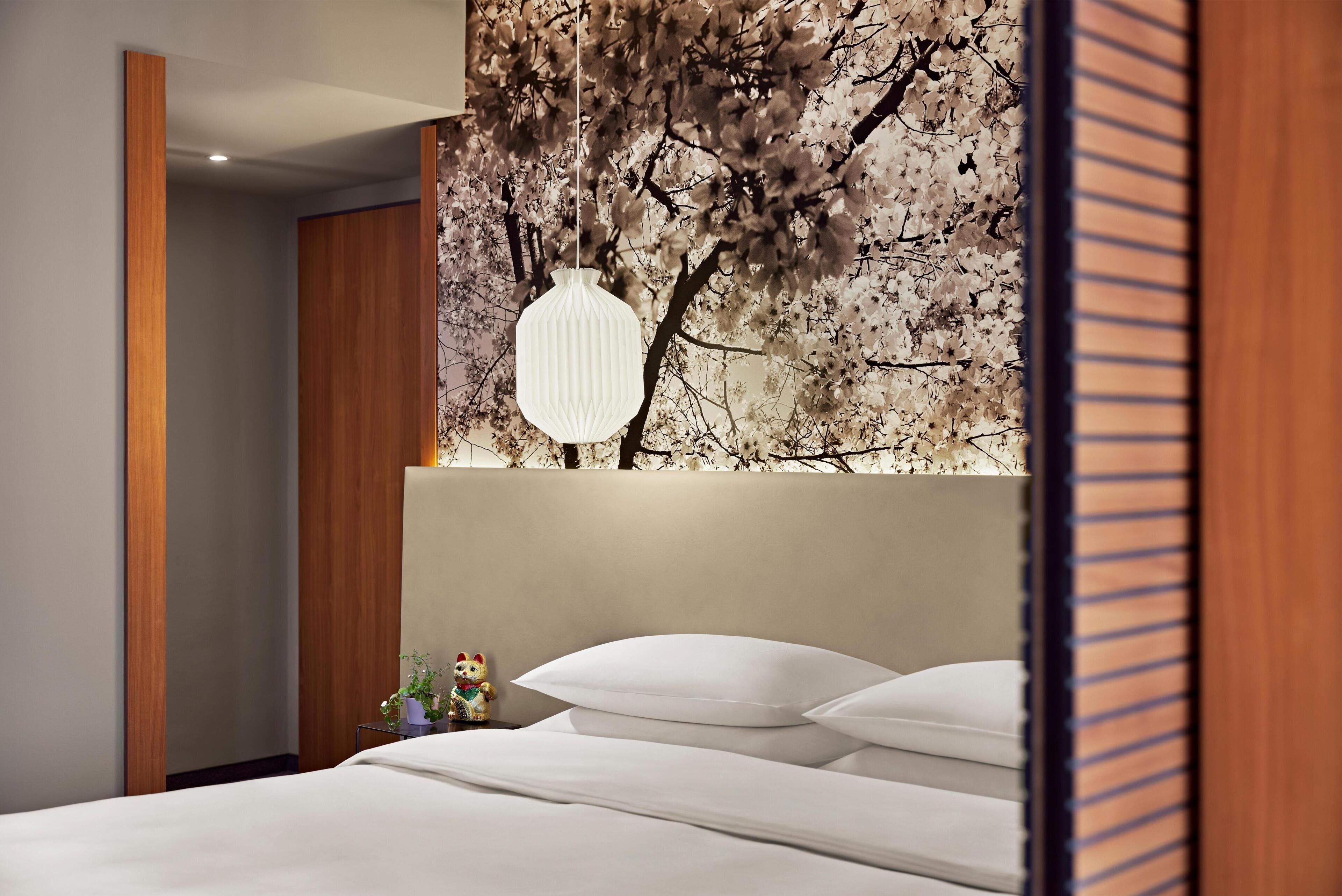 Une chambre à coucher comprenant un lit, une table de chevet, une lampe fixée au mur et un panneau décoratif mural.