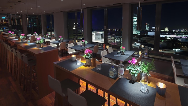 Un restaurante moderno con varias mesas, sillas y plantas en macetas.