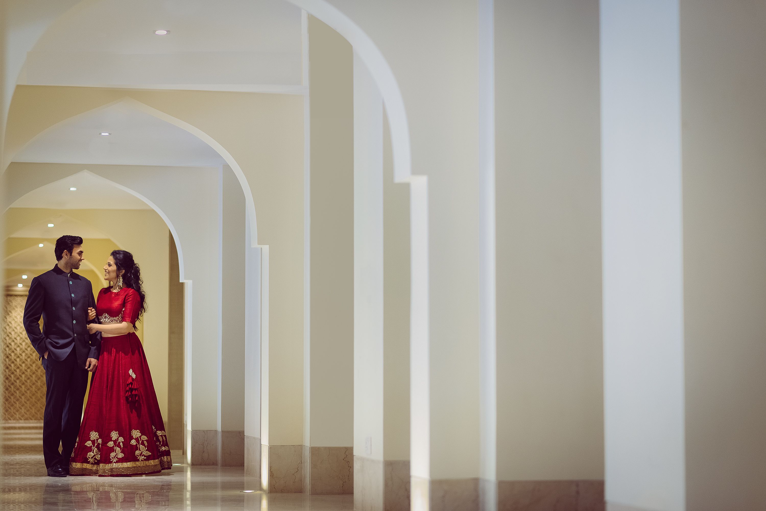 A couple in a hallway with a marble floor and white walls.