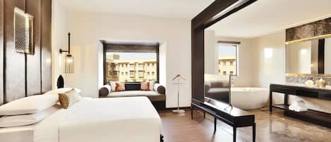 A modern hotel room with a large bed, a sitting area with a view, a bathtub, and a large mirror.