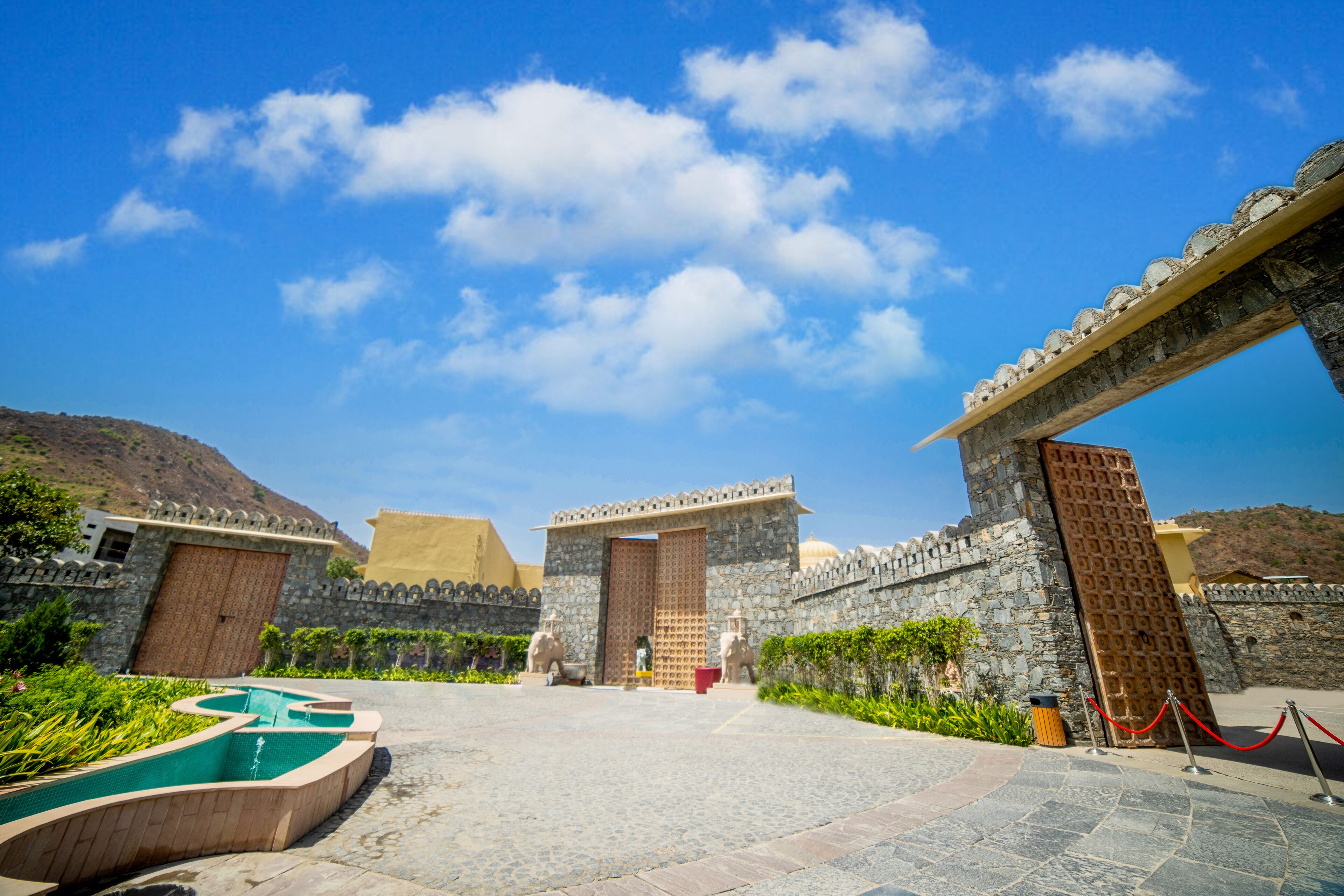 A courtyard with stone walls, a central gate, and a pool.