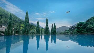 Relax by the serene pool surrounded by lush greenery and majestic mountains.