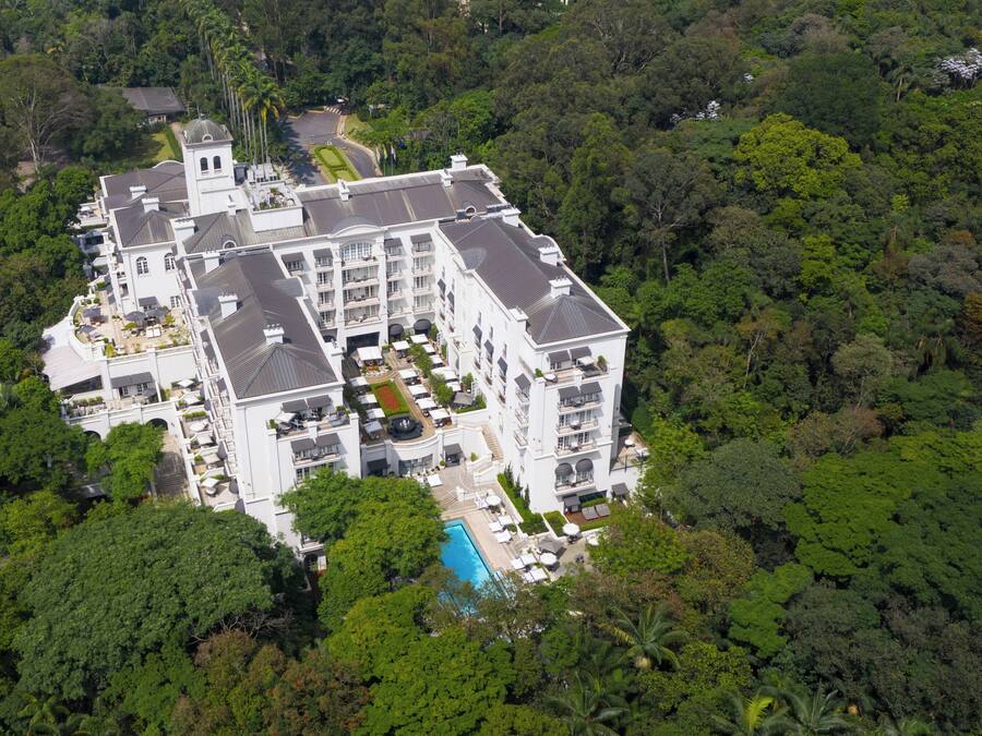 A large, multi-story hotel with a central courtyard, surrounded by dense forest.