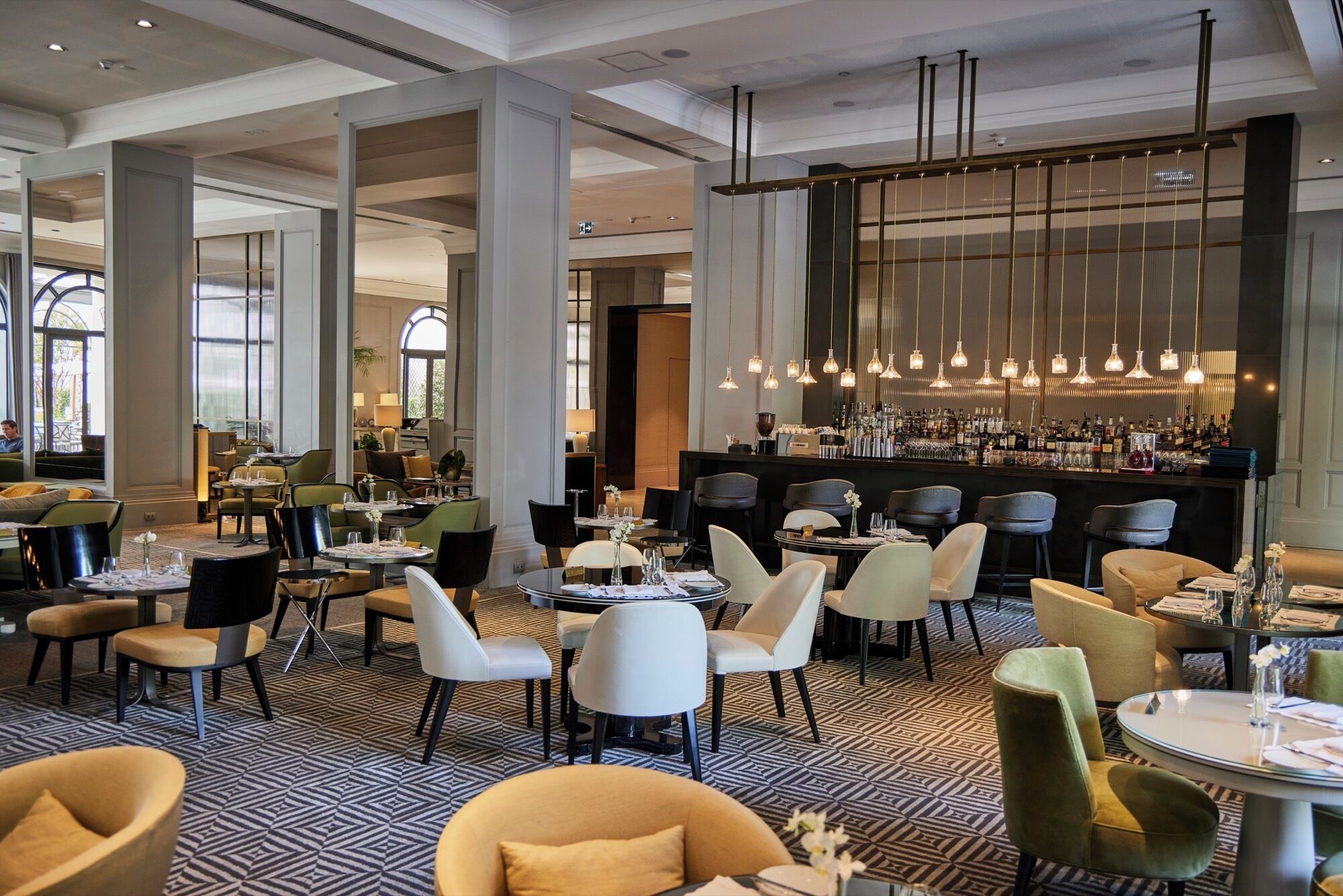 Um hall de hotel moderno com área de bar, assentos e piso estampado.