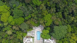 An aerial view of a resort with a central pool, surrounded by dense tropical vegetation. - Palacio Tangara, Oetker Hotels (São Paulo)