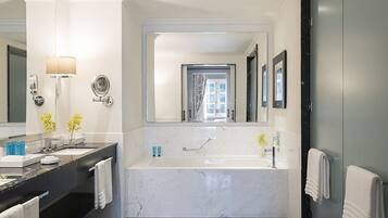 A modern bathroom with a large bathtub, a double sink vanity, and a mirror with a wall-mounted lamp.